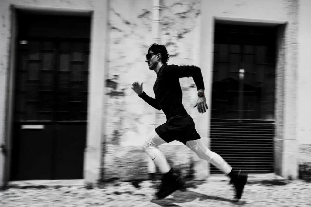 Runner wearing Apple Watch Ultra 4 while sprinting, black-and-white photo