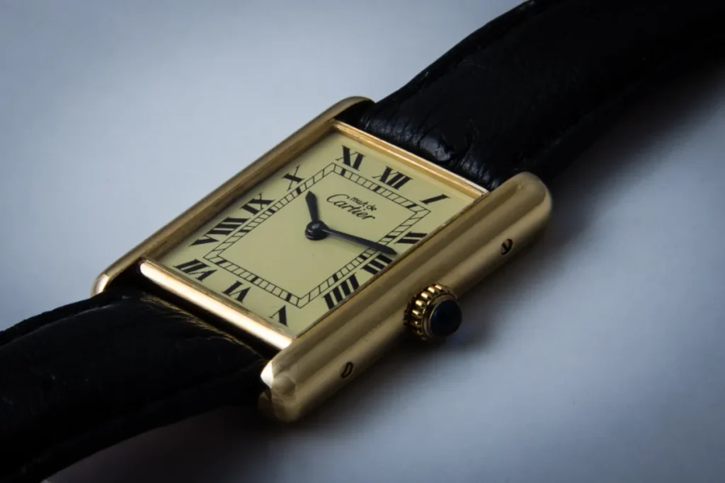 Slim gold Cartier Tank dress watch on a black leather strap