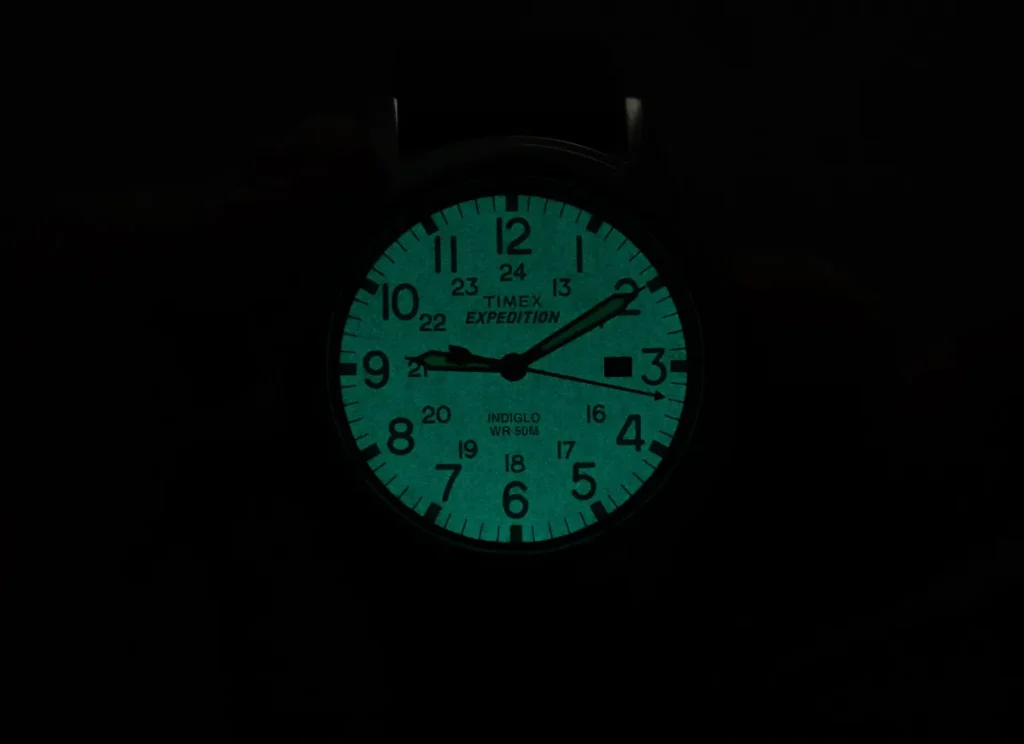 Timex Expedition watch dial lit by its blue-green Indiglo backlight